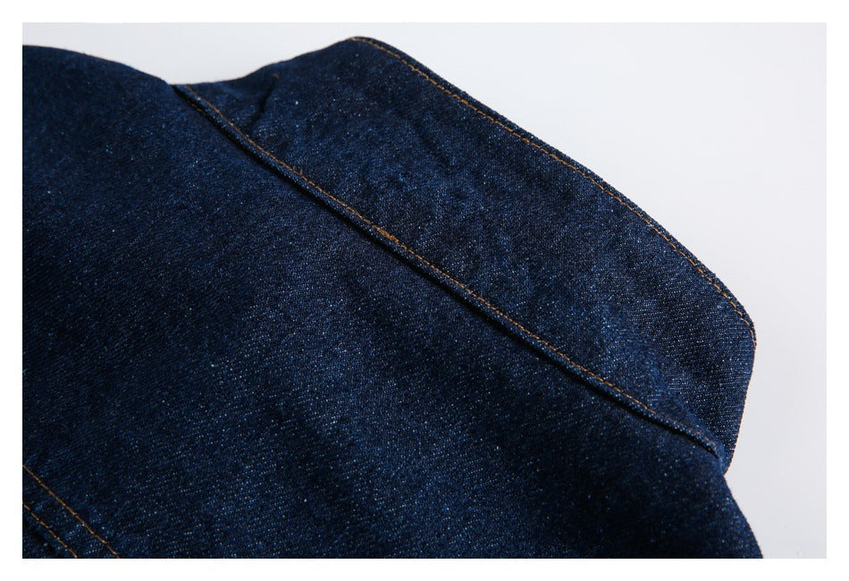Close-up of the dark indigo denim jacket collar and its orange-stitched edge.