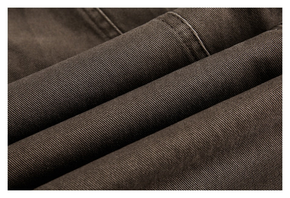 Macro view of brown trouser fabric folded into ridges, highlighting its fine diagonal weave.