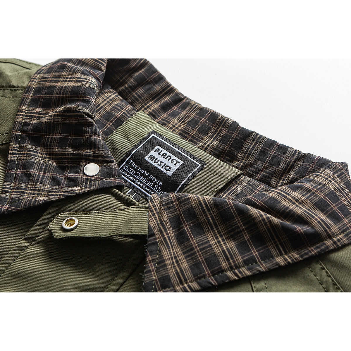 Close-up of an olive jacket with dark plaid lining, snap fasteners, and a sewn-in label.