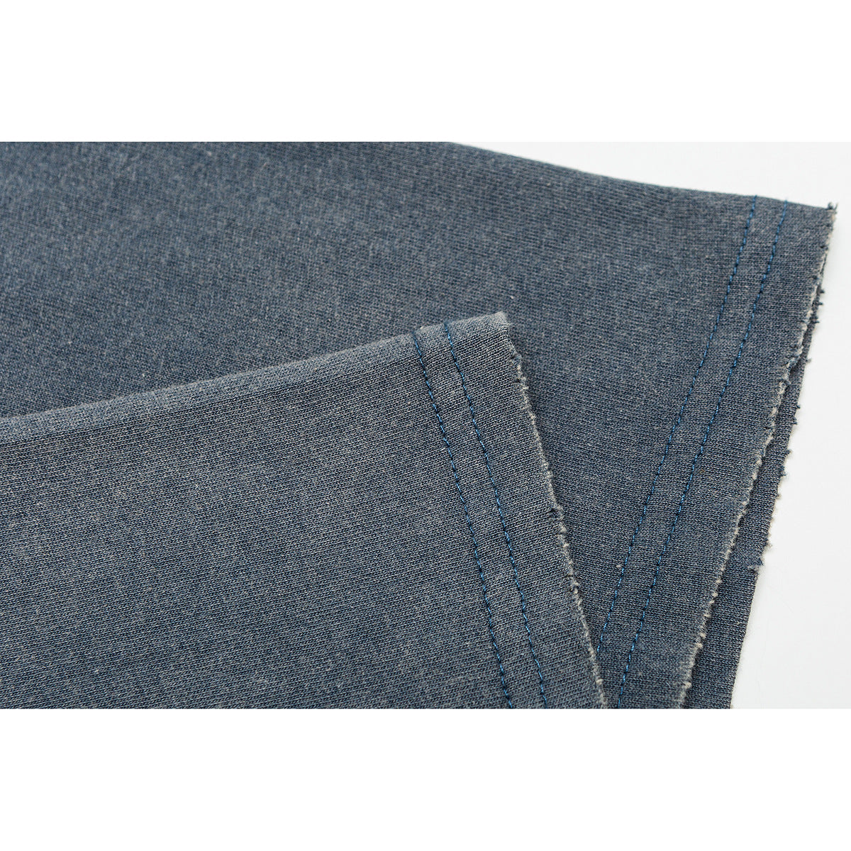 Close-up of the double-stitched hem on a faded blue T-shirt.