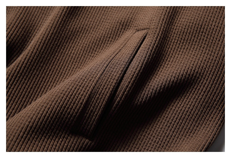 Close-up of the brown hoodie’s pocket opening and textured fabric.