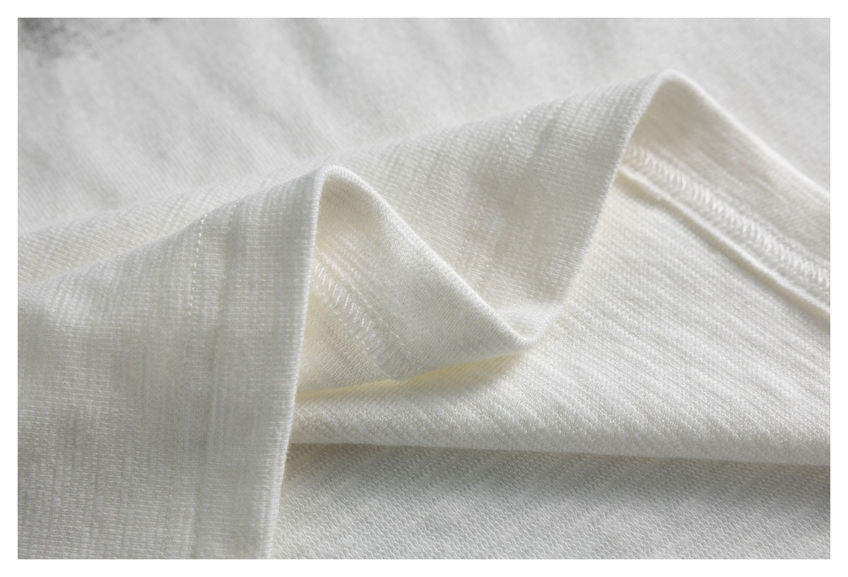 Close-up of softly folded white knit fabric with a fine textured weave.