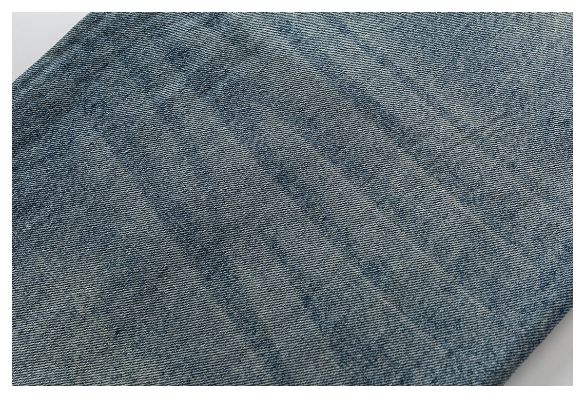 Close-up of blue denim fabric showing its diagonal weave and faded texture.