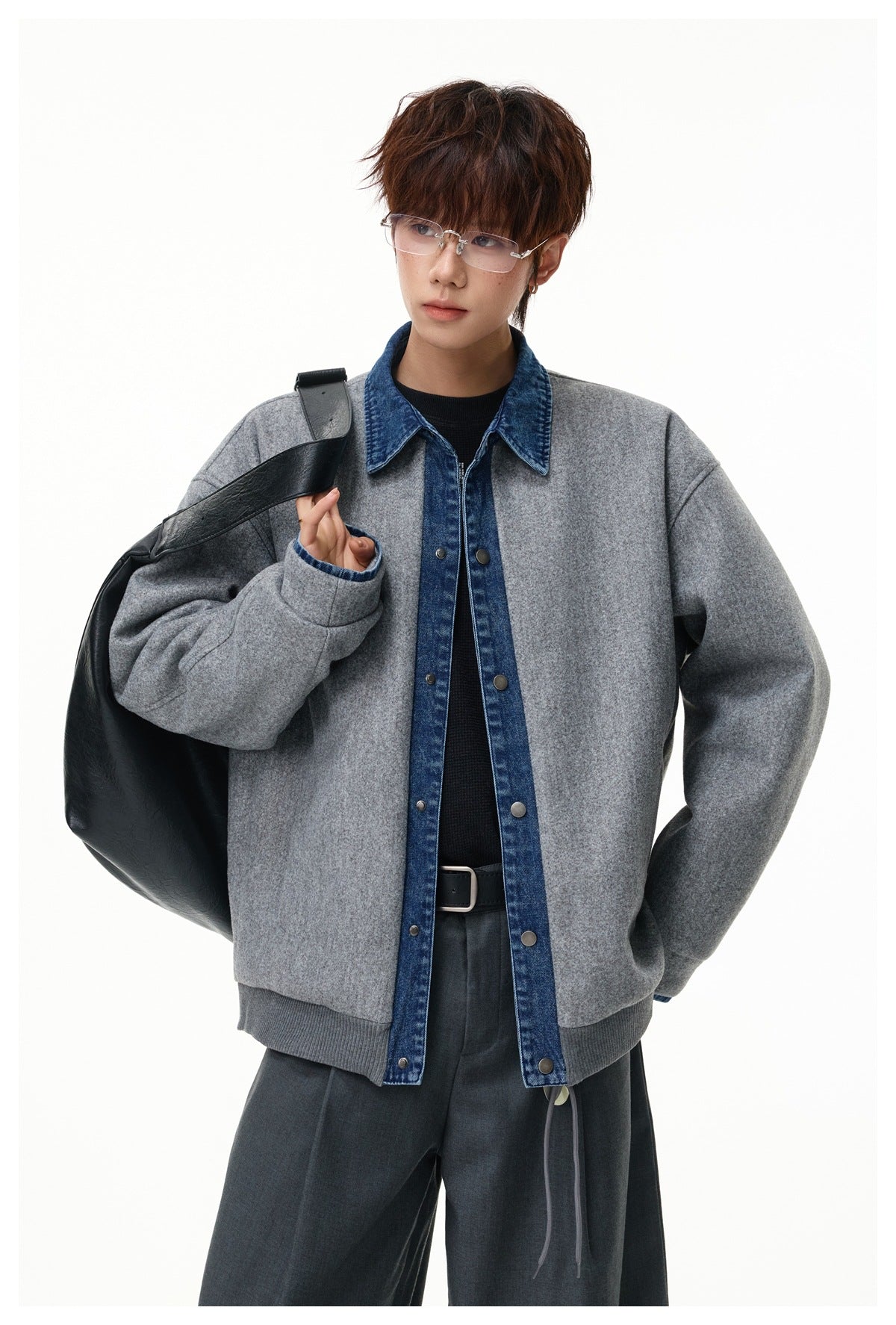 Model wearing a light gray jacket with blue denim collar and button placket, carrying a large black shoulder bag.