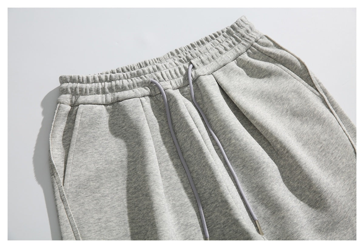 Close-up of light gray heather sweatpants showing the elastic waistband, drawstrings, and front pockets.