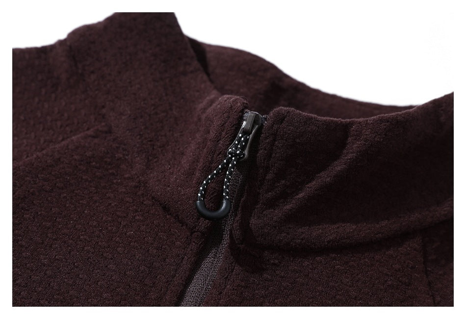 Close-up of a dark burgundy jacket's raised collar and front zipper with a looped pull.