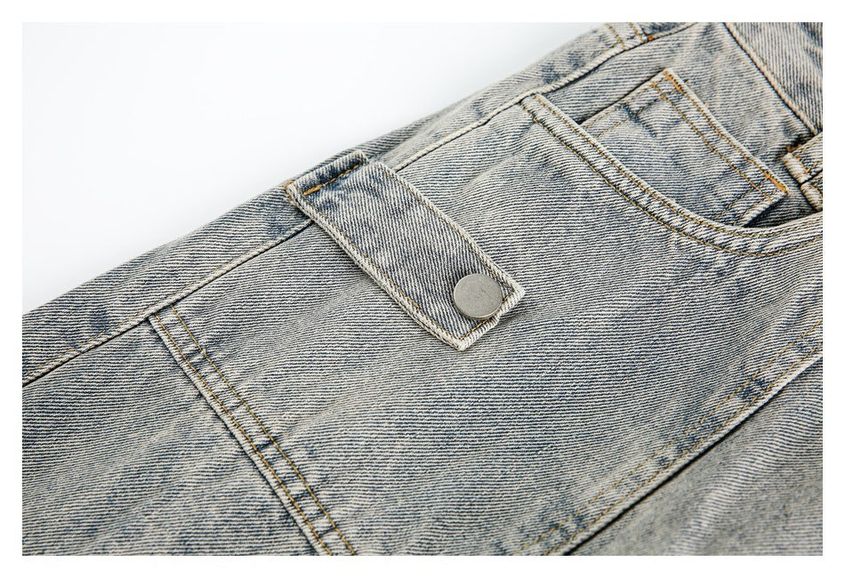 Close-up of light-wash denim waistband with a buttoned flap and contrasting gold stitching.