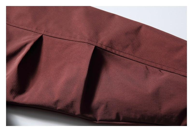 Close-up of a burgundy jacket seam and folded panel with visible stitching.