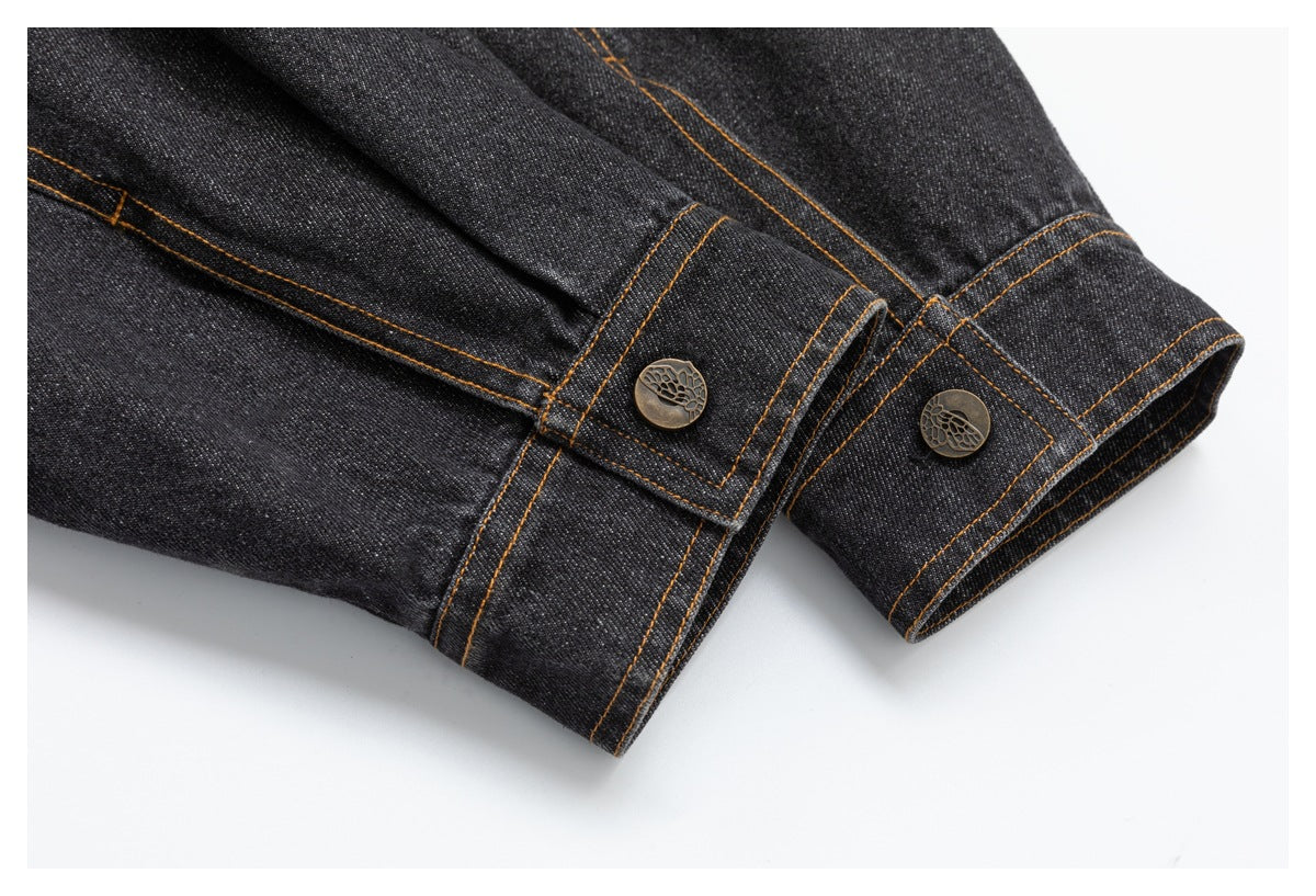 Close-up of dark denim cuffs with orange stitching and decorative metal buttons.