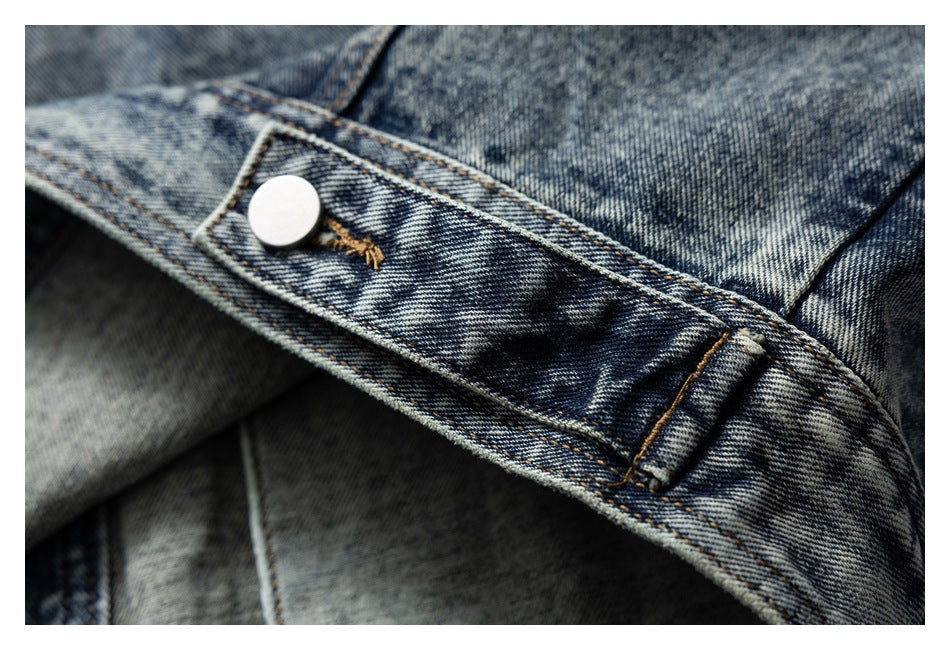 Close-up of a blue denim jacket snap tab and reinforced stitching.