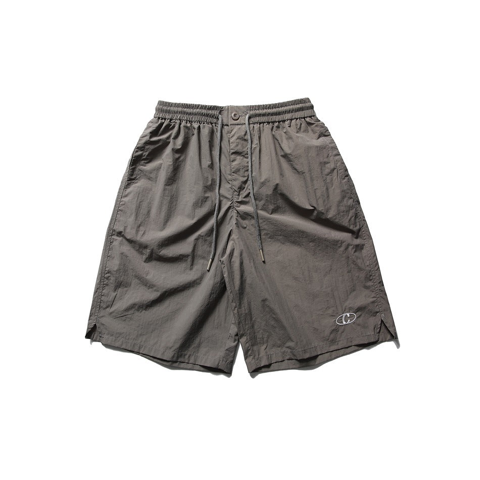 Gray taupe knee-length drawstring shorts with elastic waist and small embroidered oval logo, flat front view