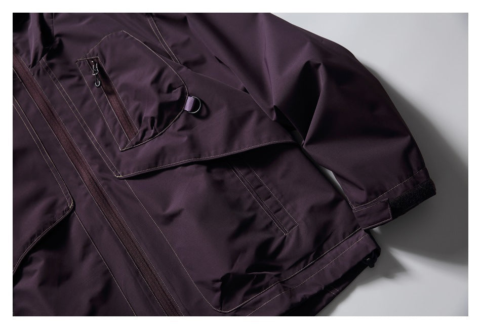 Close-up of the dark plum jacket's front pocket, sleeve cuff, and adjustable cuff tab.