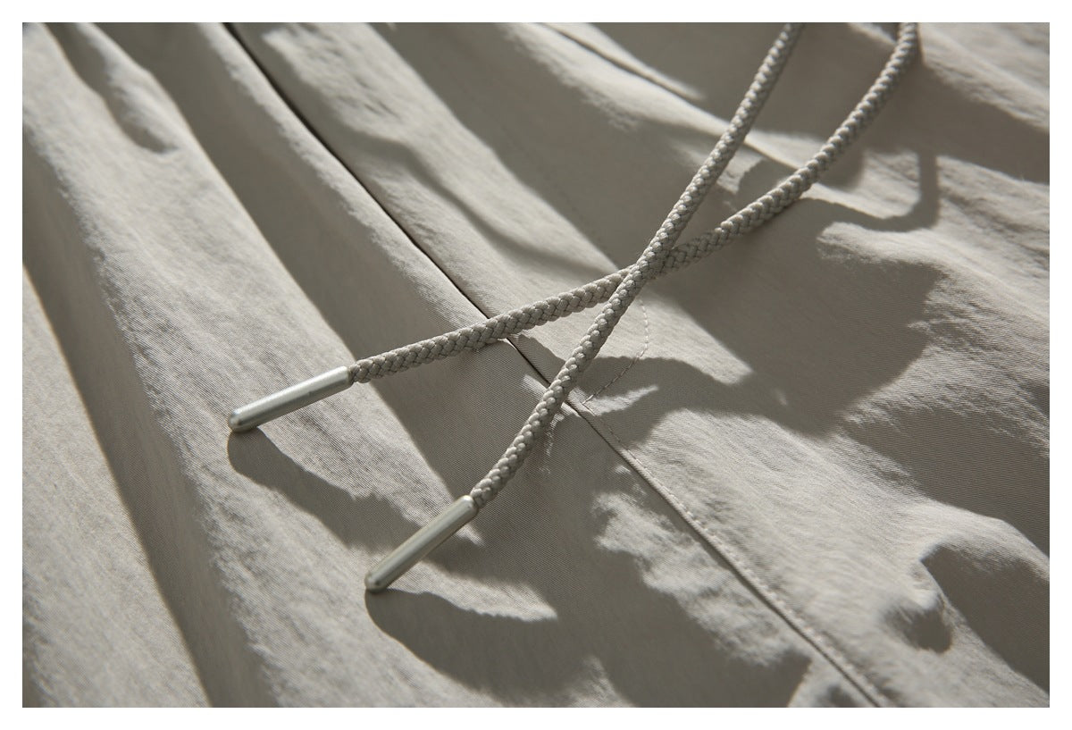 Close-up of braided drawstrings with metal tips on light beige shorts.
