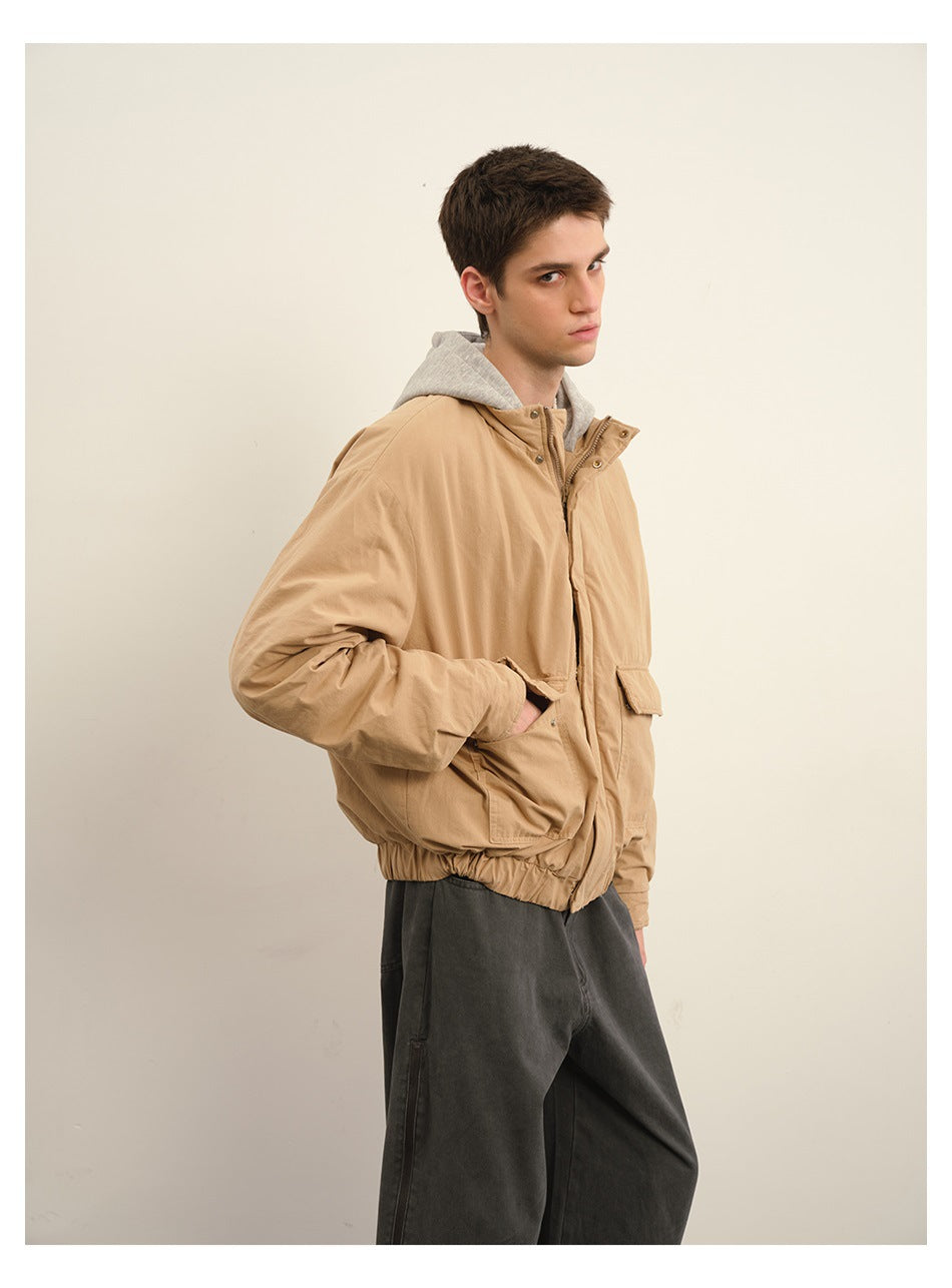 Model wearing a tan hooded jacket with a gray hood, front angled view.