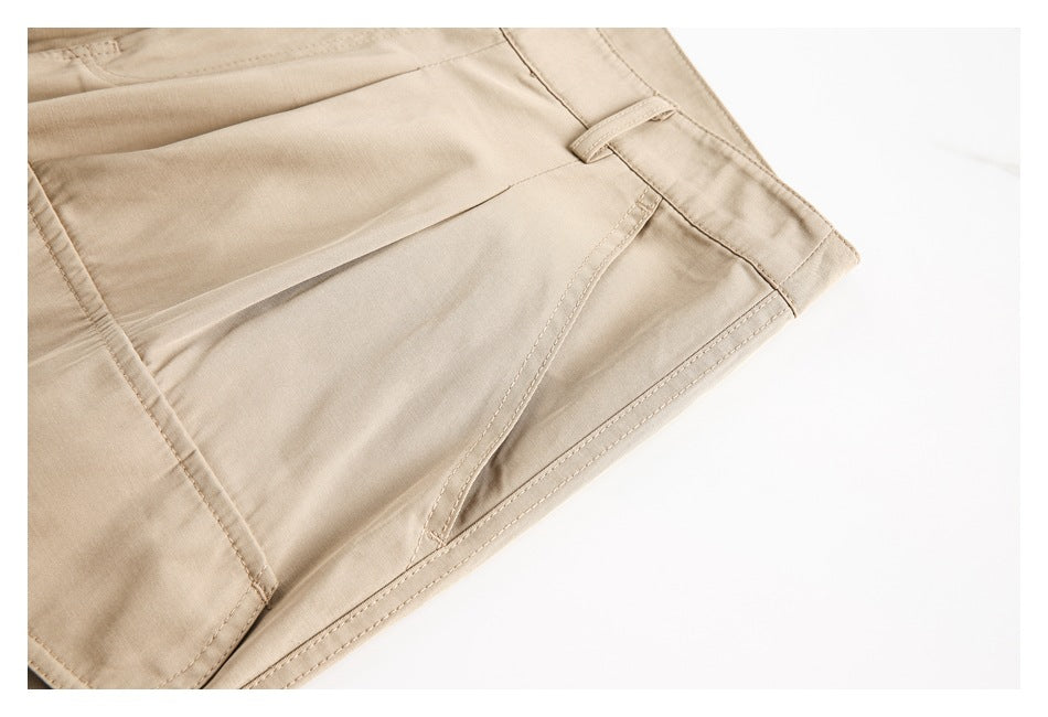 Close-up of beige trousers showing a slanted pocket opening, stitching, and waistband detail.