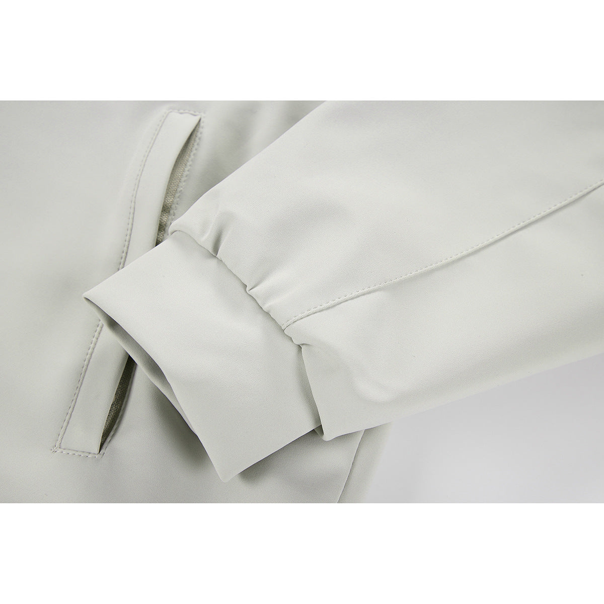 Close-up of an off-white jacket sleeve, cuff, stitching, and pocket opening.