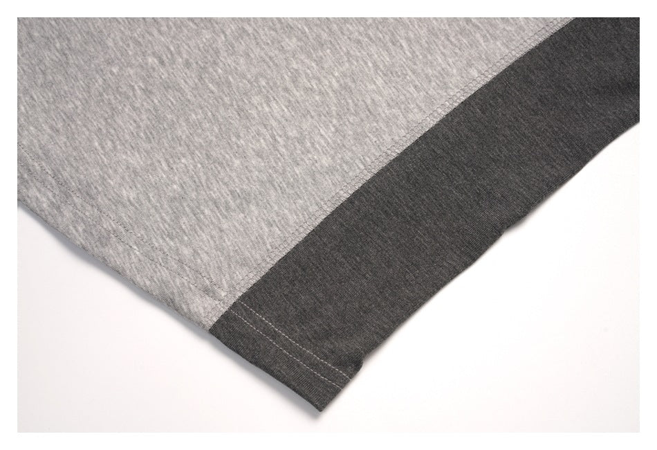Close-up of a dark charcoal contrast hem band joined to light gray heather fabric.
