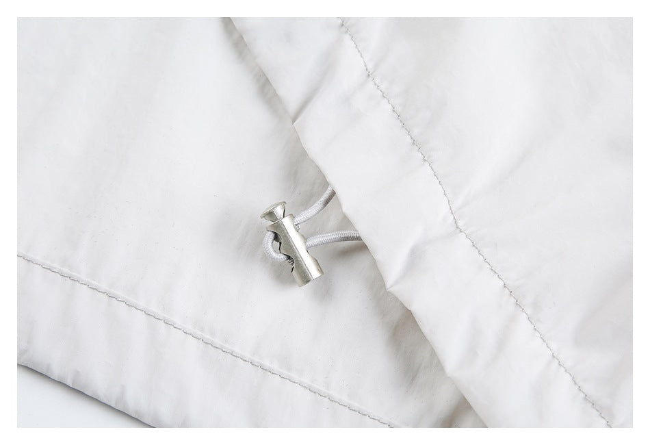 Close-up of a white jacket's drawcord and metal adjustment toggle.