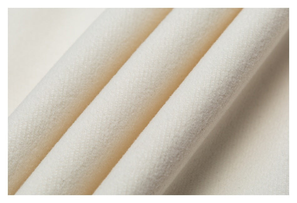 Close-up of soft-looking ivory fabric with three raised diagonal folds.