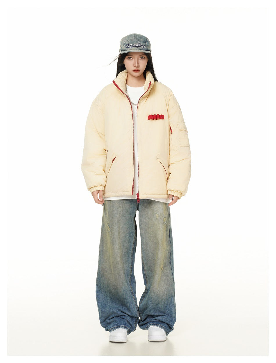 Full-length model wearing a cream padded jacket with red accents and wide distressed jeans.