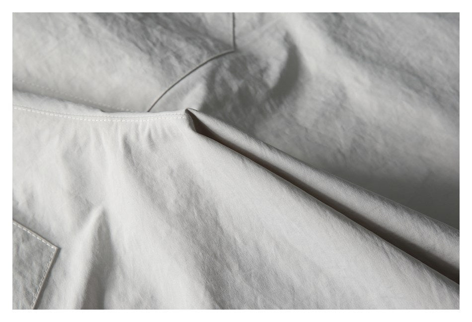 Close-up of stitching and a folded seam on a light gray garment.