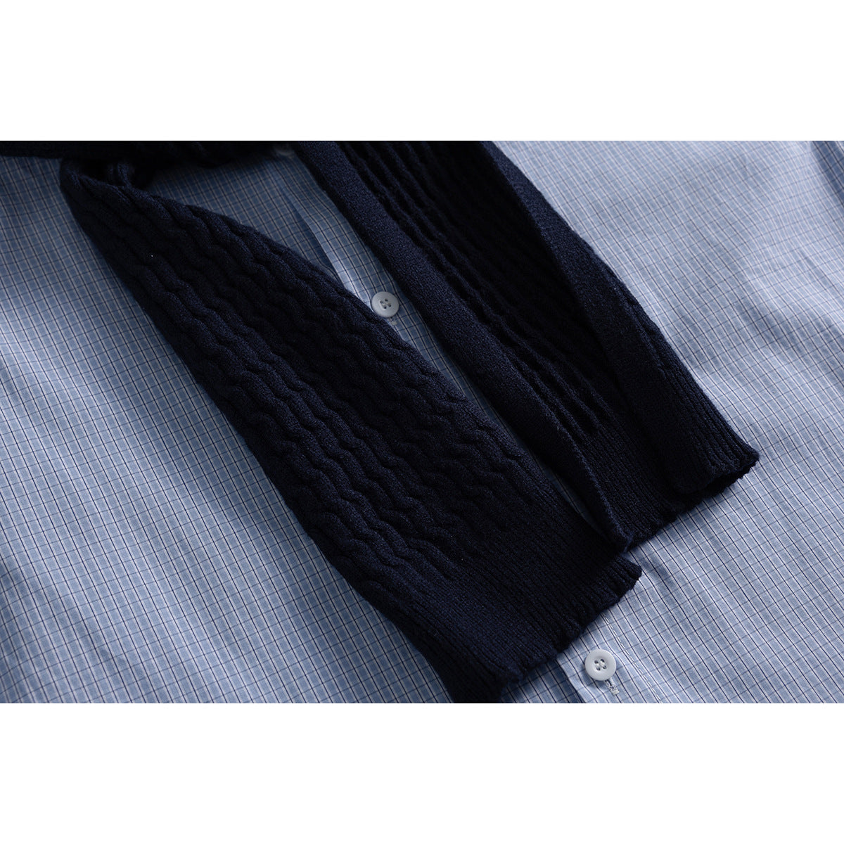 Dark navy cable-knit scarf draped diagonally over a light blue checked shirt.