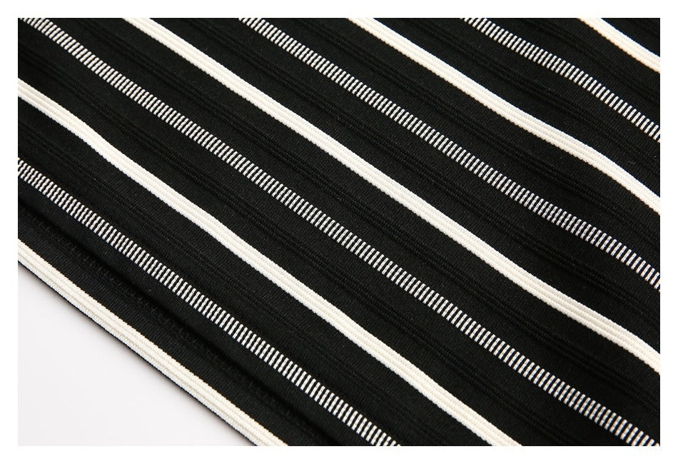 Close-up of black fabric with repeating cream and narrow white stripes.