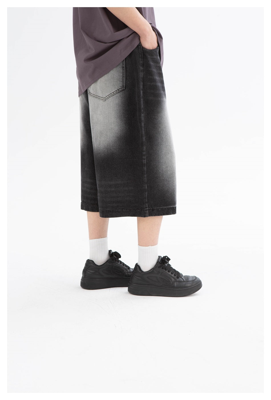 Side view of washed black wide-leg shorts with a back pocket and gray fading, worn with a charcoal shirt.