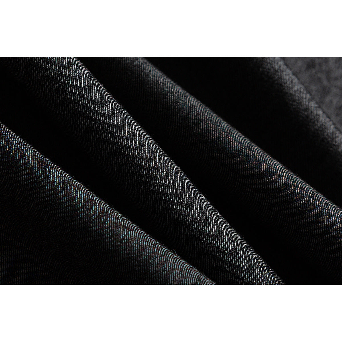 Extreme close-up of dark charcoal fabric folded to show its fine woven texture.