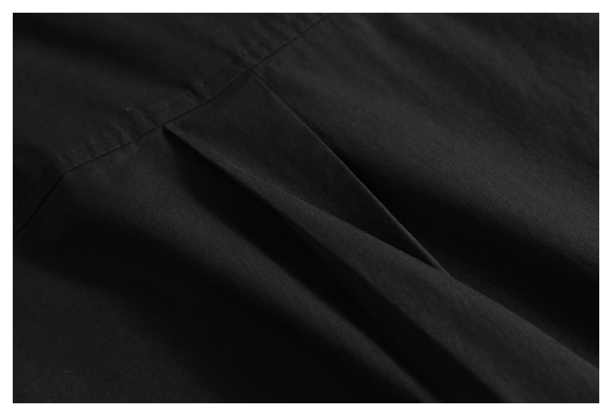 Close-up of black garment fabric with a diagonal folded opening and visible stitching.