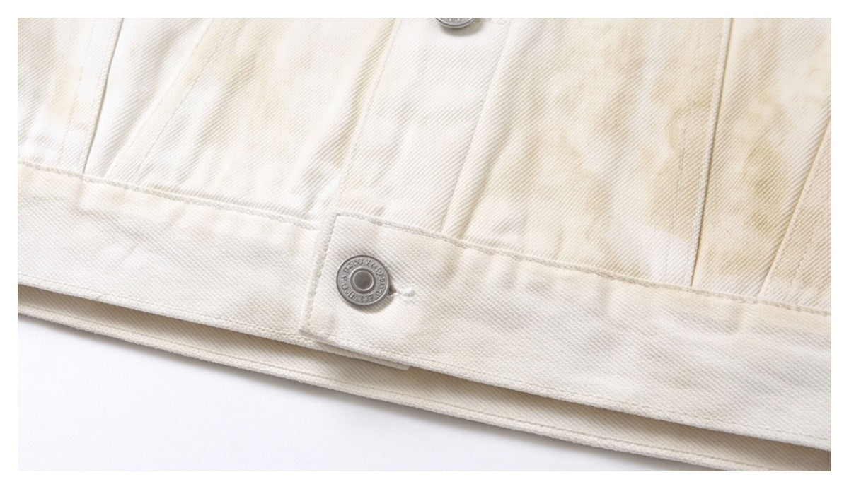 Close-up of an off-white garment hem with visible stitching and a silver snap button.