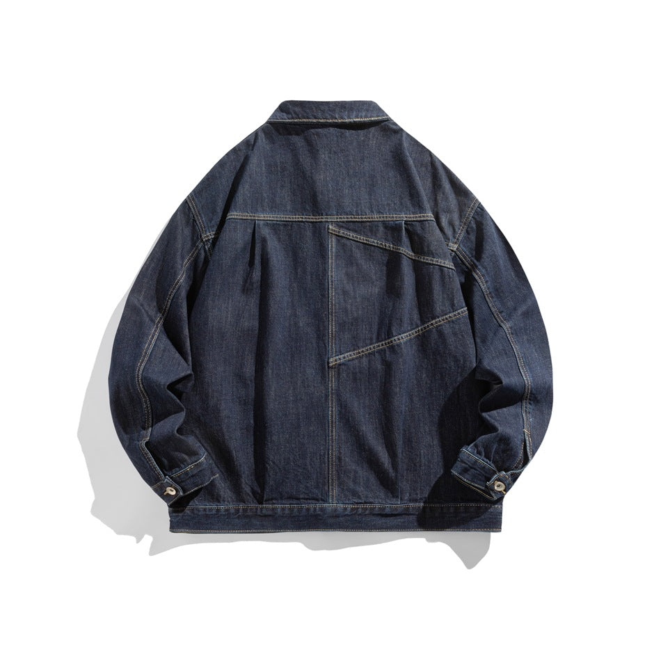 Back view of dark indigo denim jacket flat lay with pleated yoke and diagonal seam detail