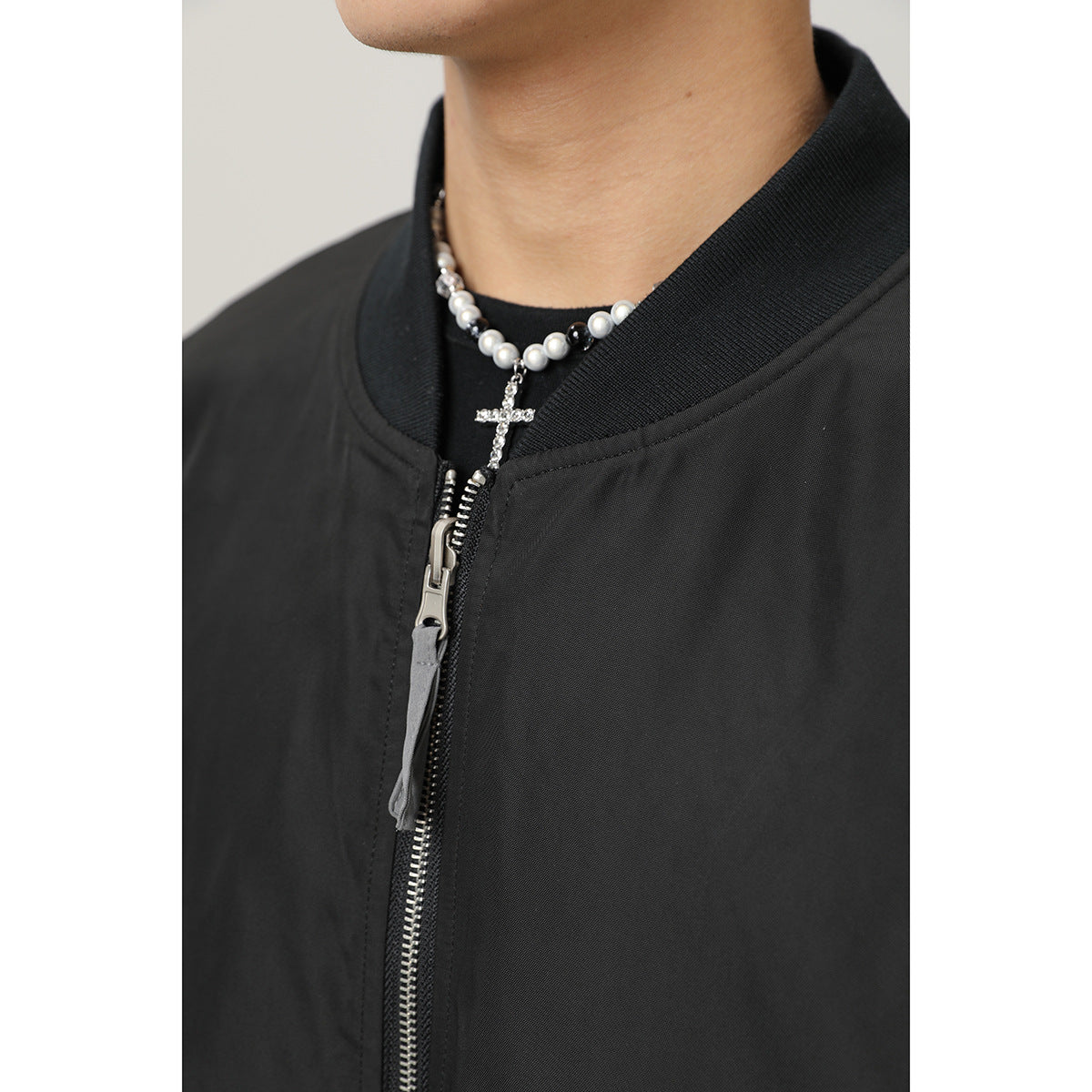 Close-up of the black bomber jacket's ribbed collar and silver front zipper.