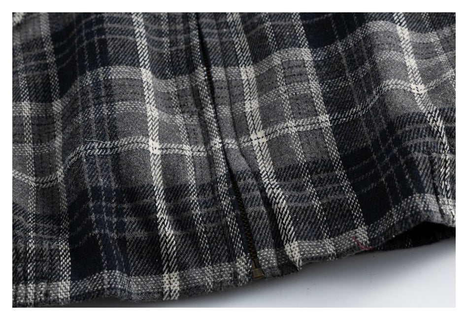 Close-up of the front zipper and lower hem of a charcoal and gray plaid jacket.