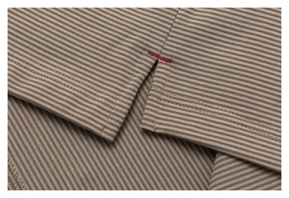 Close-up of overlapping striped fabric panels with stitched edges and a small red stitch accent.