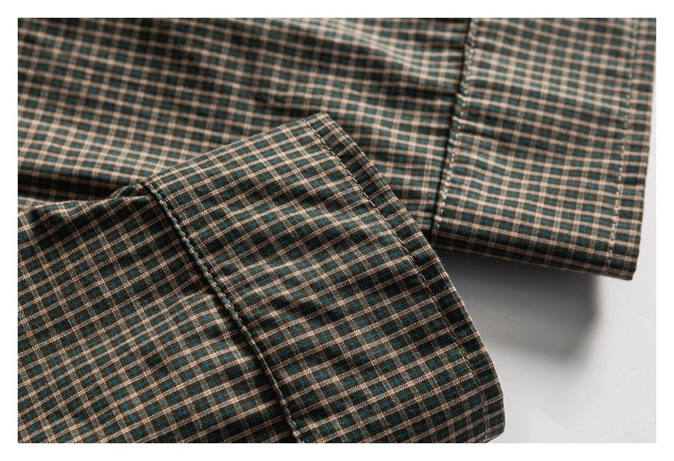 Close-up of a green, brown, and cream plaid cuff against matching plaid fabric.