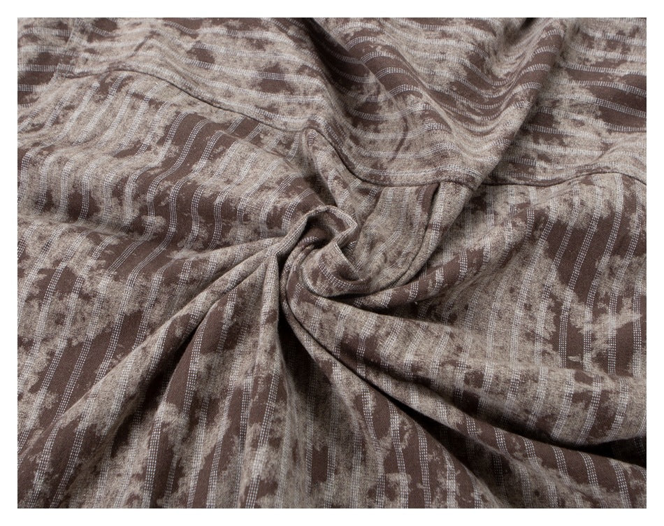Brown and beige patterned shirt fabric gathered into folds to show its texture and print.