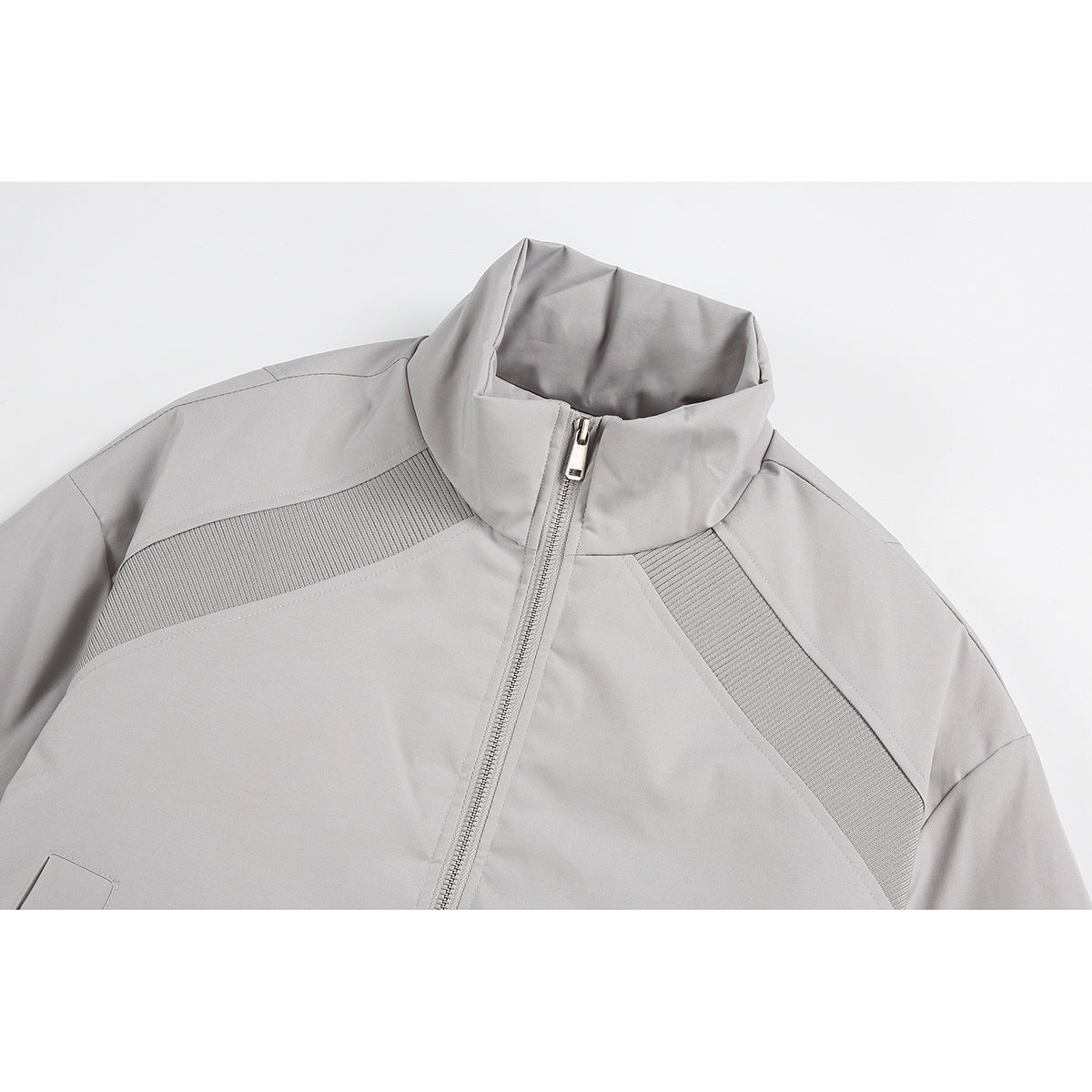 Close-up of a light gray jacket's stand collar, front zipper, and textured shoulder panels.