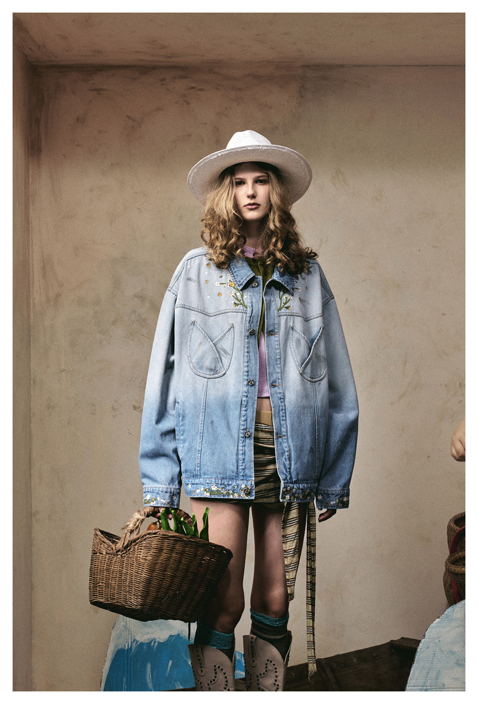 Front view of a model wearing an oversized light blue embroidered jacket with large pockets and floral cuffs.