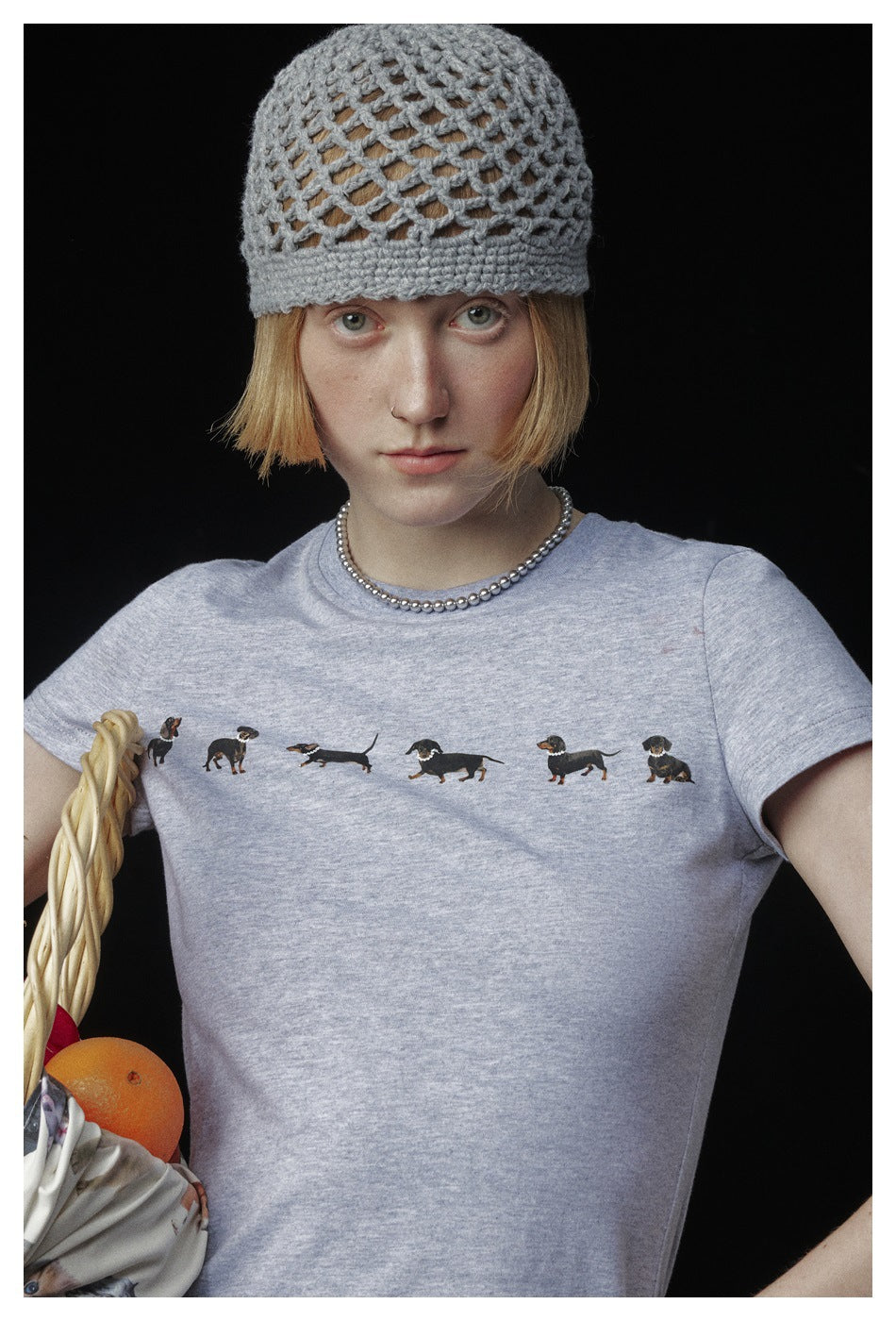 Model wearing a light gray T-shirt printed with a row of small dachshund illustrations.