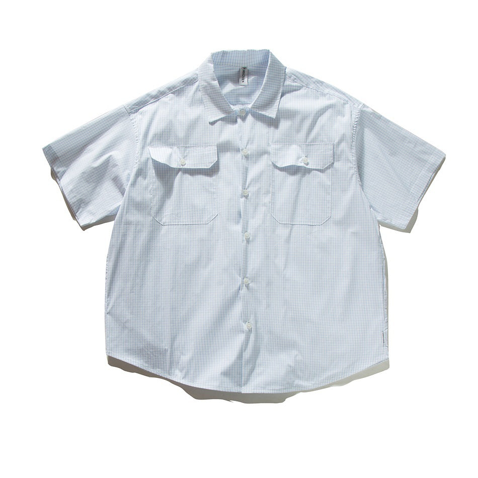 White short-sleeve button-up shirt with light blue grid check, two flap chest pockets and pointed collar, flat lay