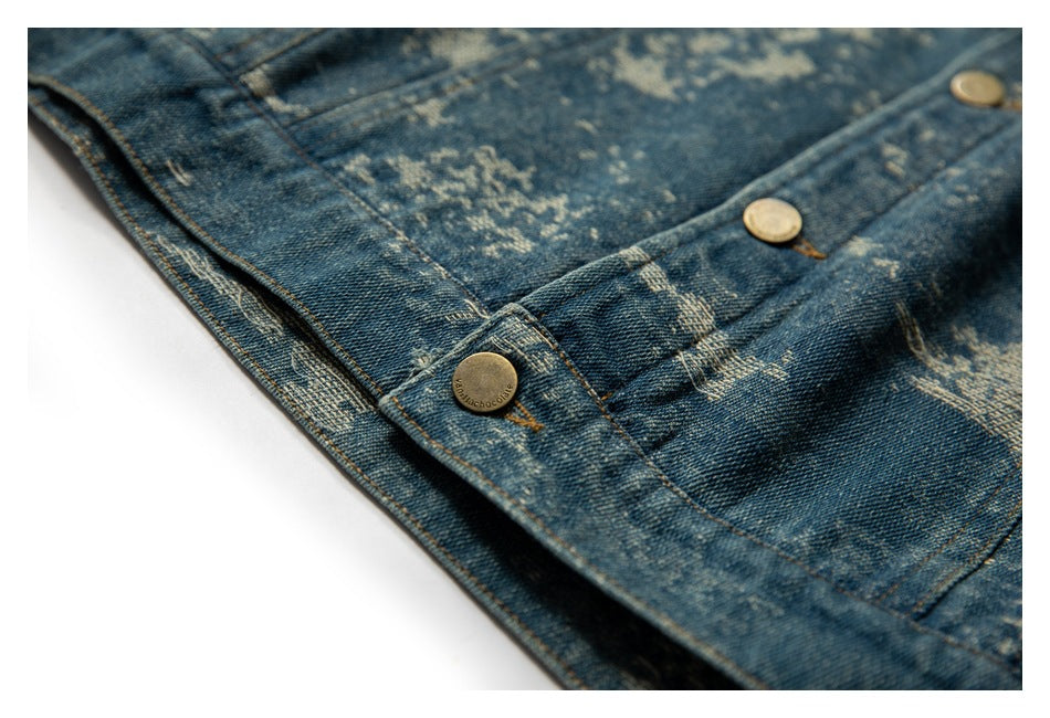 Close-up of distressed blue denim with metal buttons, a pocket edge, and contrasting seams.