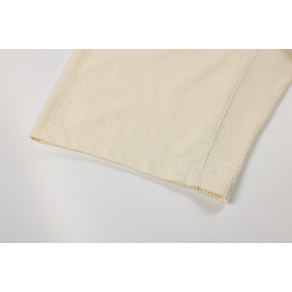 Close-up of an ivory sweatshirt sleeve hem and adjacent ribbed panel.
