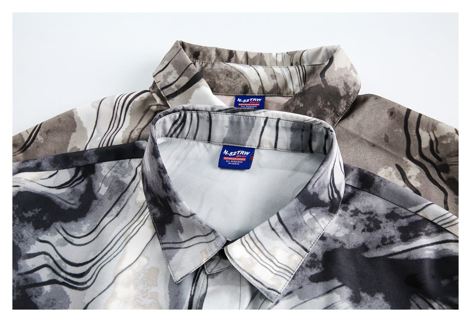 Close-up of two overlapping gray, black, and cream abstract-print shirts showing their pointed collars and sewn-in labels.