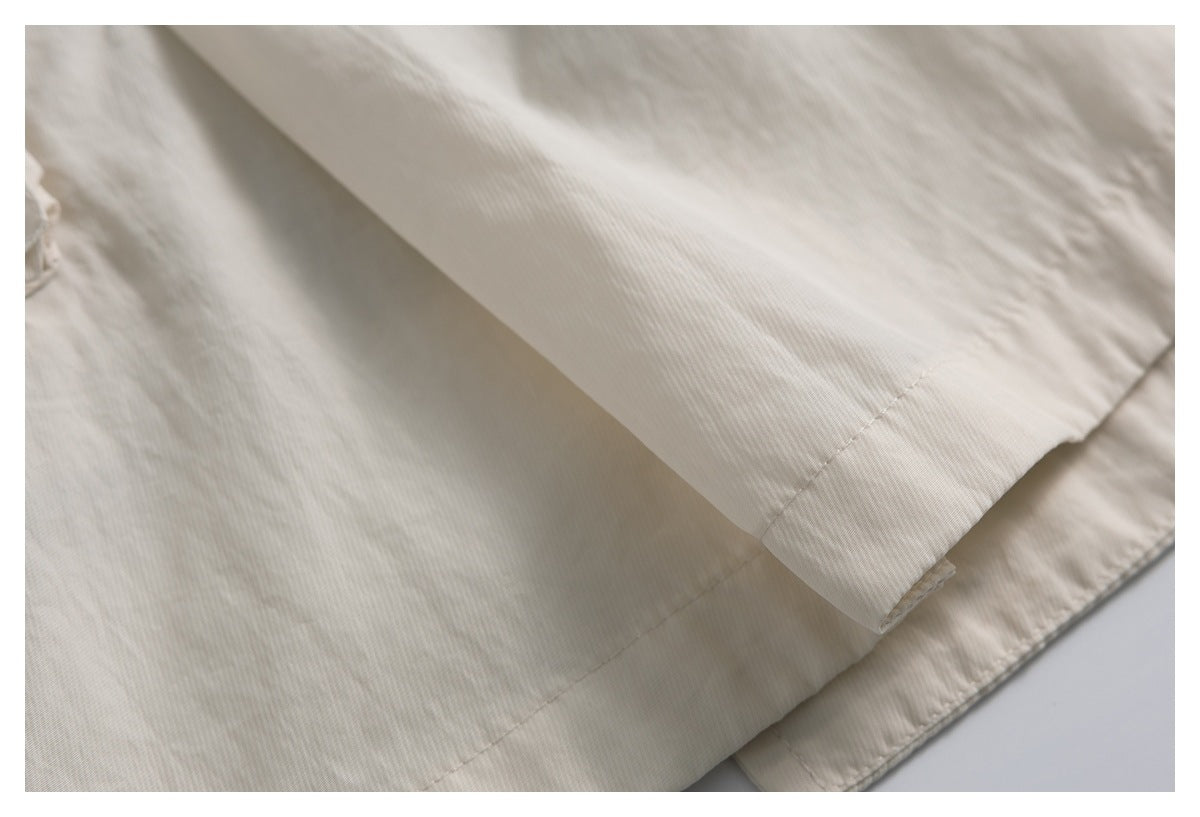 Close-up of the ivory garment's stitched hem and layered fabric edge.