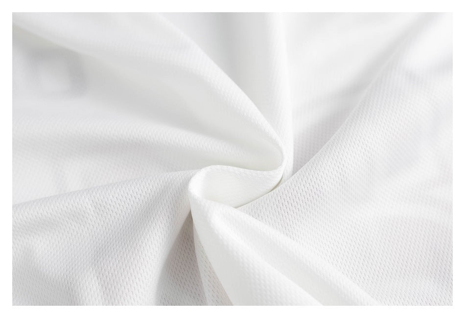 Close-up of white fabric gathered into folds, showing a small repeating textured pattern.