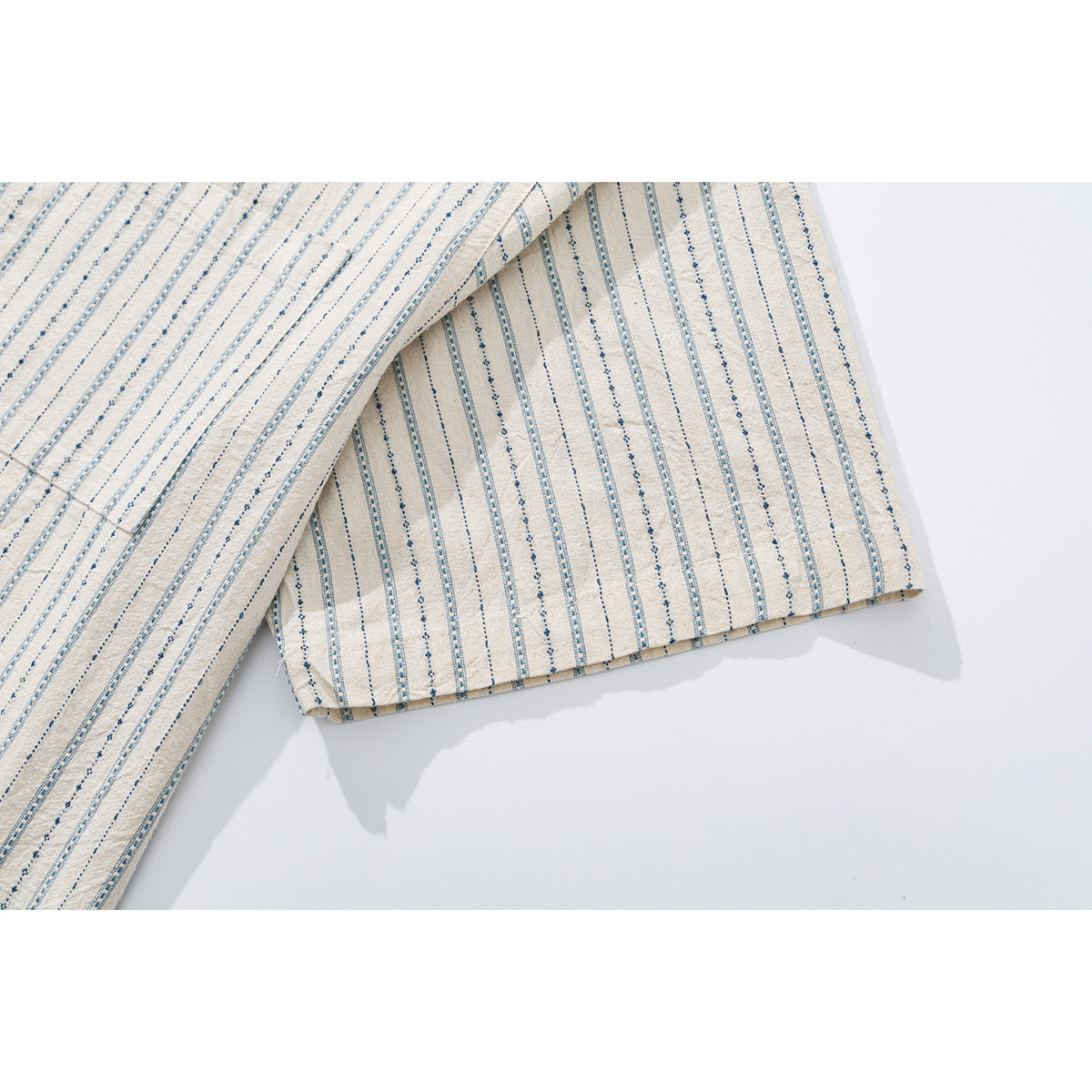 Close-up of the short sleeve and cuff of a cream shirt with narrow blue patterned stripes.