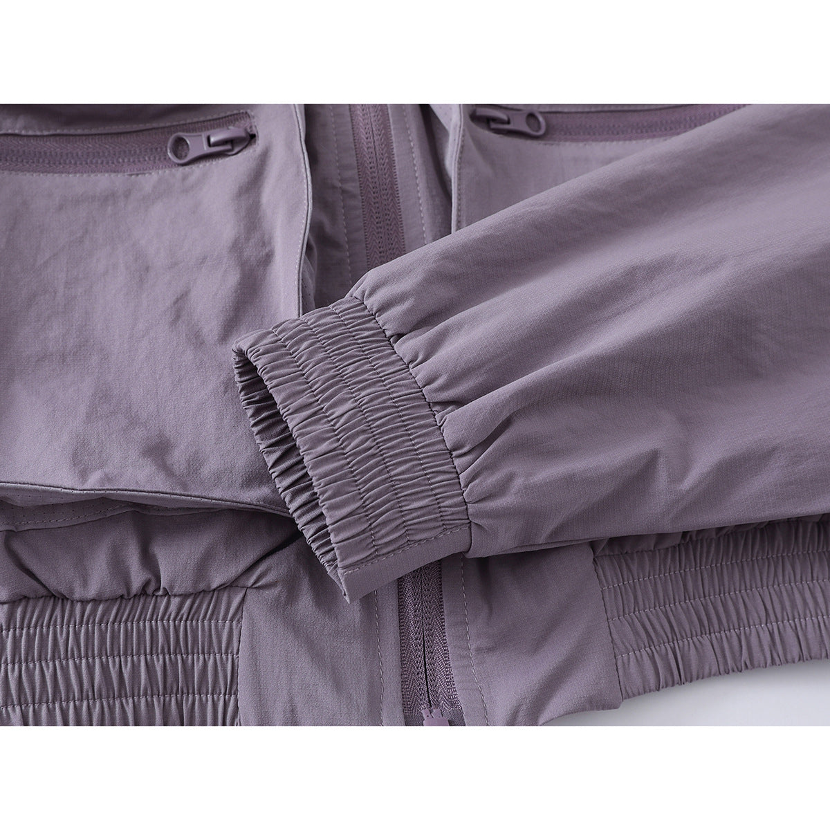 Close-up of the jacket's gathered sleeve cuff and elasticated hem in muted lavender-gray.