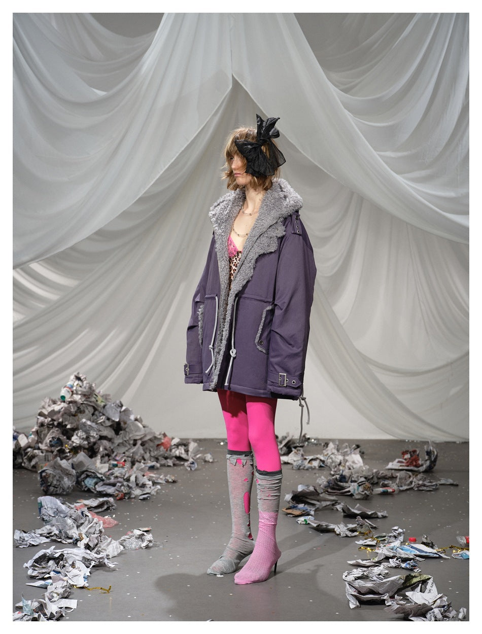 Side view of a model wearing a dark purple parka with a gray plush collar and adjustable drawcords.