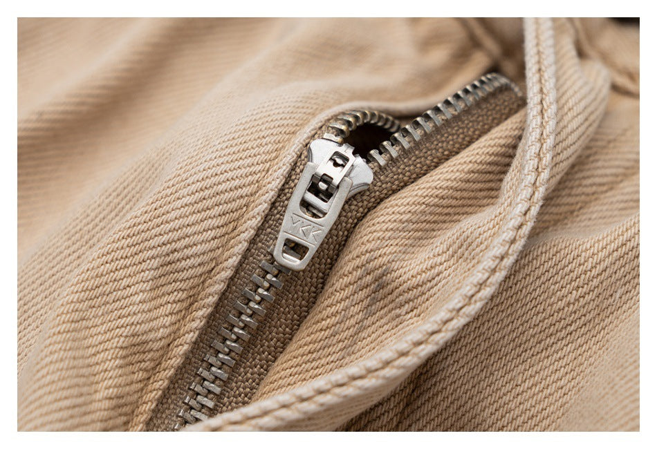 Close-up of the metal zipper and beige twill fabric on the trousers.